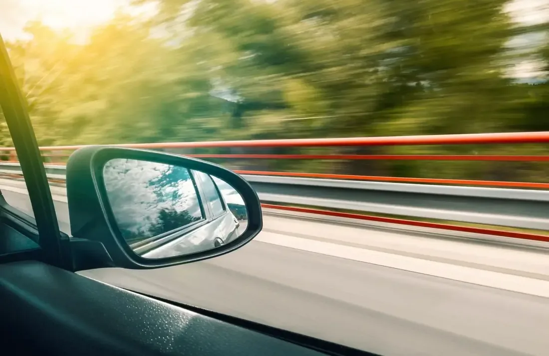 Vue depuis le rétroviseur d'une voiture roulant sereinement sur autoroute