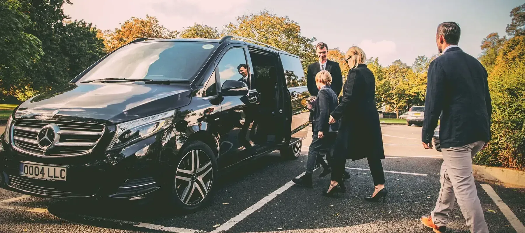 Client lisant un journal à l'intérieur d'une voiture, avec un chauffeur en costume au premier plan